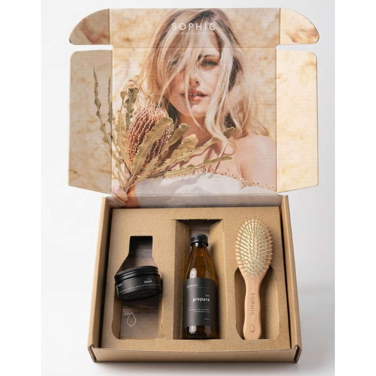 Skincare product set with bottles and a brush in a cardboard box, featuring a photo of a woman on the lid.